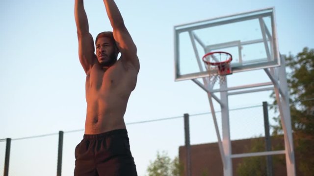 african american sporty man with naked torso warming up in morning on basketball court slow motion 
