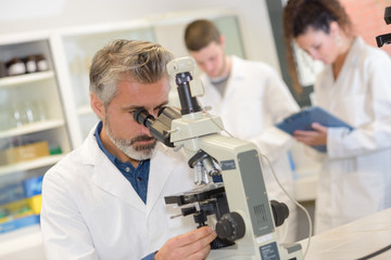 closeup of mature male scientist using microscope in laboratory