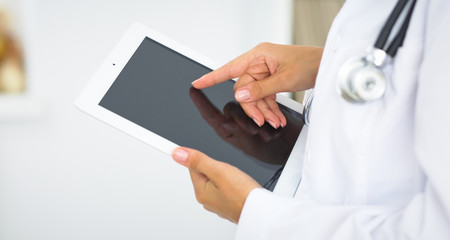 Woman doctor using tablet computer while standing straight in hospital