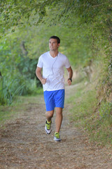 young handsome runner with earphones outside in nature