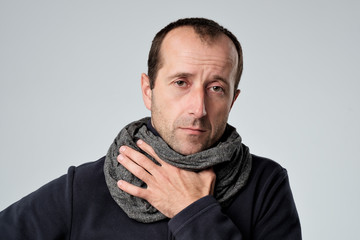 Caucasian man in scarf with headache and sore throat has cold