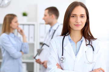 Young beautiful female doctor smiling  on the background with patient  in hospital