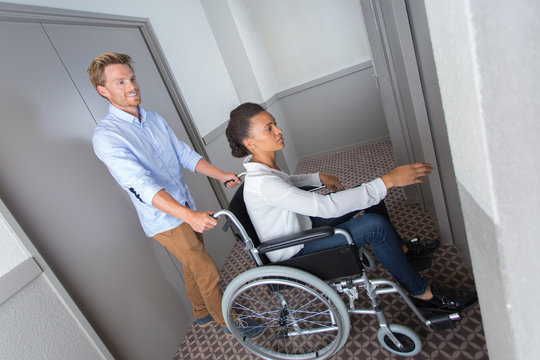 disabled businesswoman with her colleague pushing her in a lift