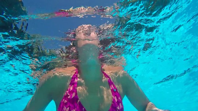 Woman swimming in pool at sunny day.