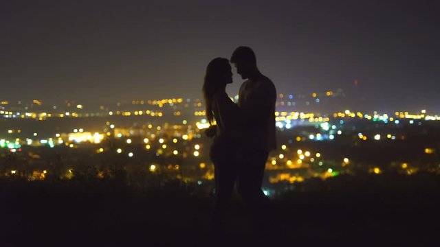 The couple kissing on the background of the city lights. Night time