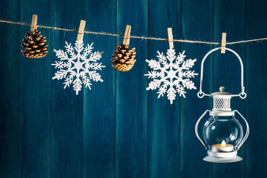 Christmas background. Candle lantern, fir cones and snowflakes on clothespin on deep blue wooden background with copy space. Christmas or New Year card template.