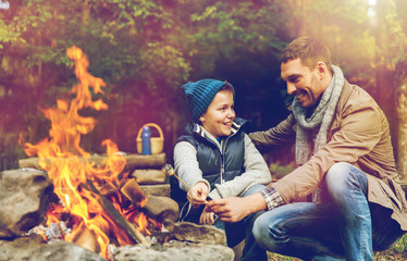 father and son roasting marshmallow over campfire