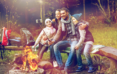 family with smartphone taking selfie near campfire