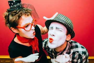 two mimes posing against a red wall background