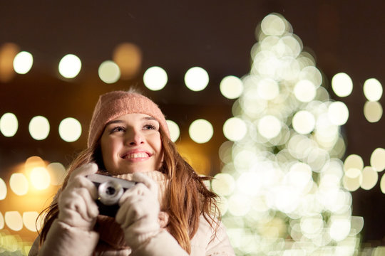 happy young woman with camera over christmas tree