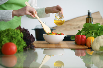 Closeup of human hands cooking vegetables salad in kitchen on the glass  table with reflection