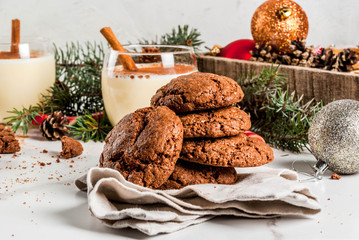 Chocolate Crinkle cookies for Christmas, with eggnog cocktail, candy cane, Christmas tree and holiday decoration, on white marble table, copy space