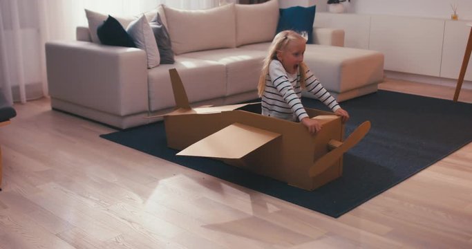 CINEMAGRAPH - seamless loop. Cute dreamer girl child playing in a cardboard airplane. Childhood. Fantasy, imagination concept. 4K UHD