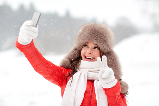happy woman taking selfie outdoors in winter