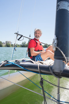 handsome mature man sailing on a lake