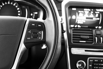 Media control buttons on the steering wheel in black leather with computer monitor, modern car...