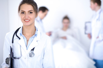 Female doctor smiling on the background with patient in the bed
