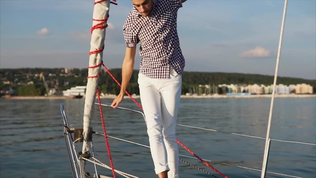 An active and outrageous man dances on a motor boat in the daytime summer, bright and energetic person move to music on a yacht during a trip on the sea
