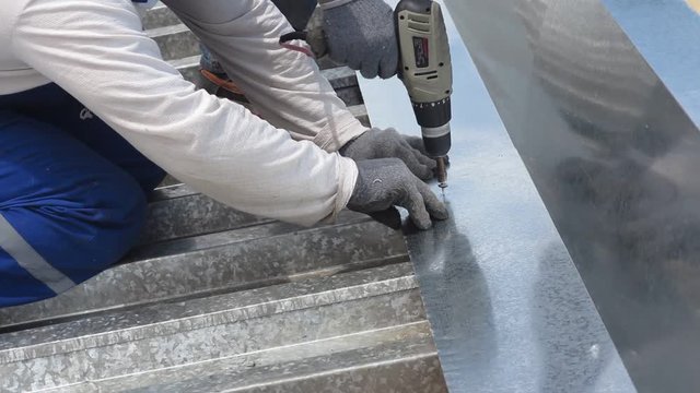 The roofer drills metal a drill