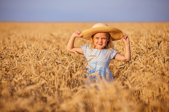 Cute little girl playing in the summer field of wheat