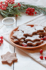 Traditional Christmas gingerbread cookies, stars in powdered sugar on the plate. Berries of red Rowan branch spruce.