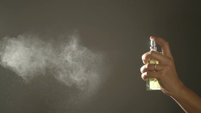 Slow motion,Woman spraying fragrance with scent particles.
