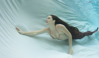 Model underwater in a pool wearing a swimsuit.