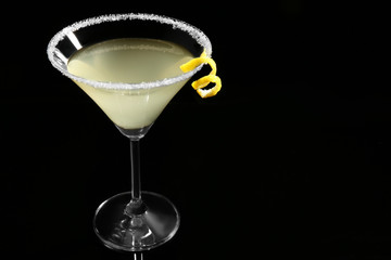 Glass of lemon drop martini with zest on black background