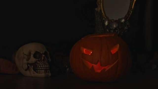 Carved Halloween pumpkin lights inside with flame and skuls around.