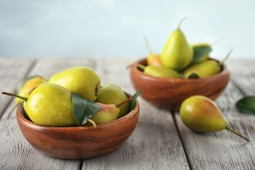 Ripe pears in bowl on wooden table