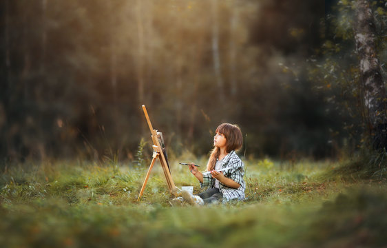 Little girl painting at easel in autumn park 