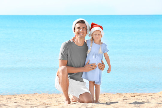 Young father with cute girl on beach. Christmas celebration concept