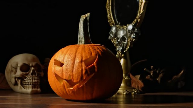 Carved Halloween pumpkin lights inside with flame and skuls around.