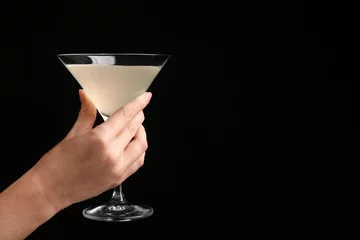 Foto auf Acrylglas Woman holding glass of lemon drop martini on black background © Africa Studio