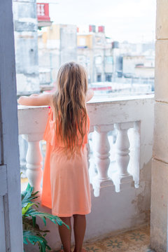 Little girl on old balcony in apartment looking on the street in Old Havana, Cuba.
