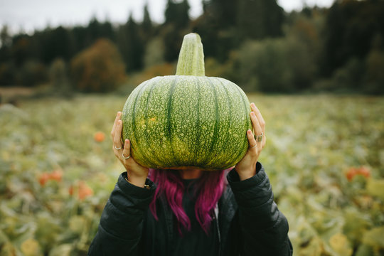 Woman With Purple Hair Holding Unusual Green Pumpkin In Front Of