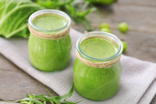 Healthy smoothie with kale in glass jars on table