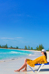 Fototapeta na wymiar Young woman on a tropical beach relaxing on sunbed