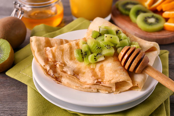 Delicious pancakes with kiwi on table