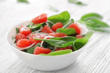 Plate of salad with spinach and grapefruit on table