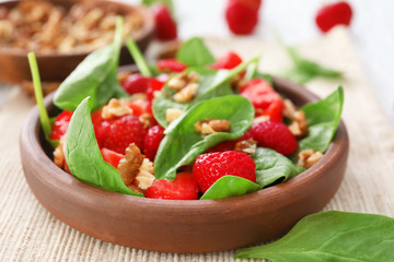 Plate of salad with spinach, strawberry and walnuts on table, closeup
