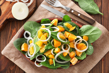 Plate with salad with spinach and orange on table