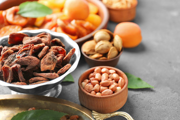 Dried apricots and nuts in different dishes on table
