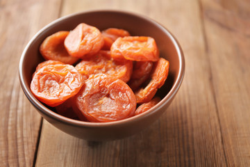 Dried apricots in bowl on wooden table