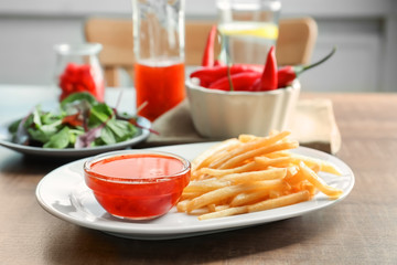 Plate with french fries and chili sauce on kitchen table