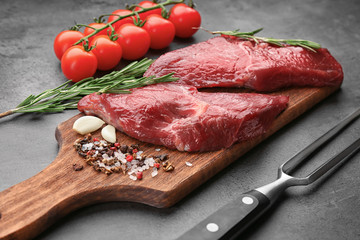 Two raw steaks with rosemary and spices on kitchen table