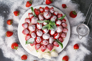 Delicious cake decorated with strawberries and sugar powder on grey background