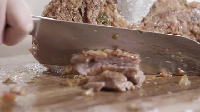 Chef cuts braised beef on cutting board, close up