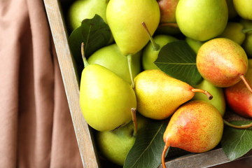 Ripe pears in wooden basket on fabric