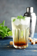 Glass with mint julep on wooden table